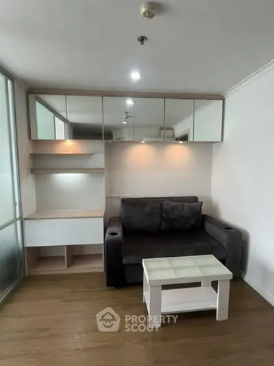 Modern living room with sleek sofa and glass coffee table, featuring built-in storage and ambient lighting.