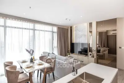 Luxurious open-plan living room with dining area and modern decor, featuring large windows and elegant furnishings.