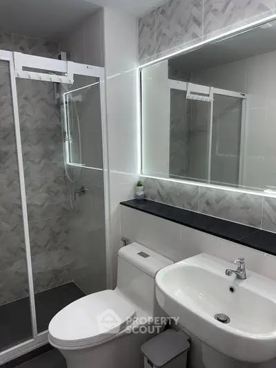 Modern bathroom with sleek shower and illuminated mirror in stylish apartment.