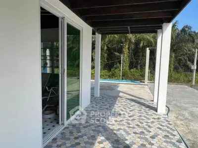 Charming patio with tiled flooring and sliding glass doors, surrounded by lush greenery.