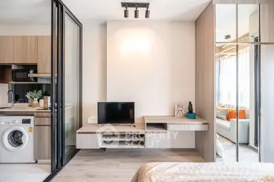 Modern studio apartment with open kitchen and cozy living area, featuring sleek design and natural light.