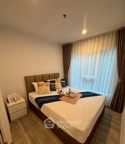 Cozy bedroom with elegant decor and large window for natural light.