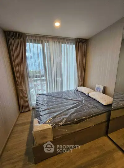 Modern bedroom with large window and stylish curtains in a cozy apartment.