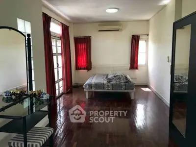 Spacious bedroom with wooden flooring and natural light
