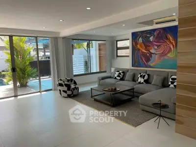 Modern living room with large sofa, abstract art, and poolside view