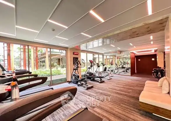 Modern gym with state-of-the-art equipment and garden view in luxury apartment complex.