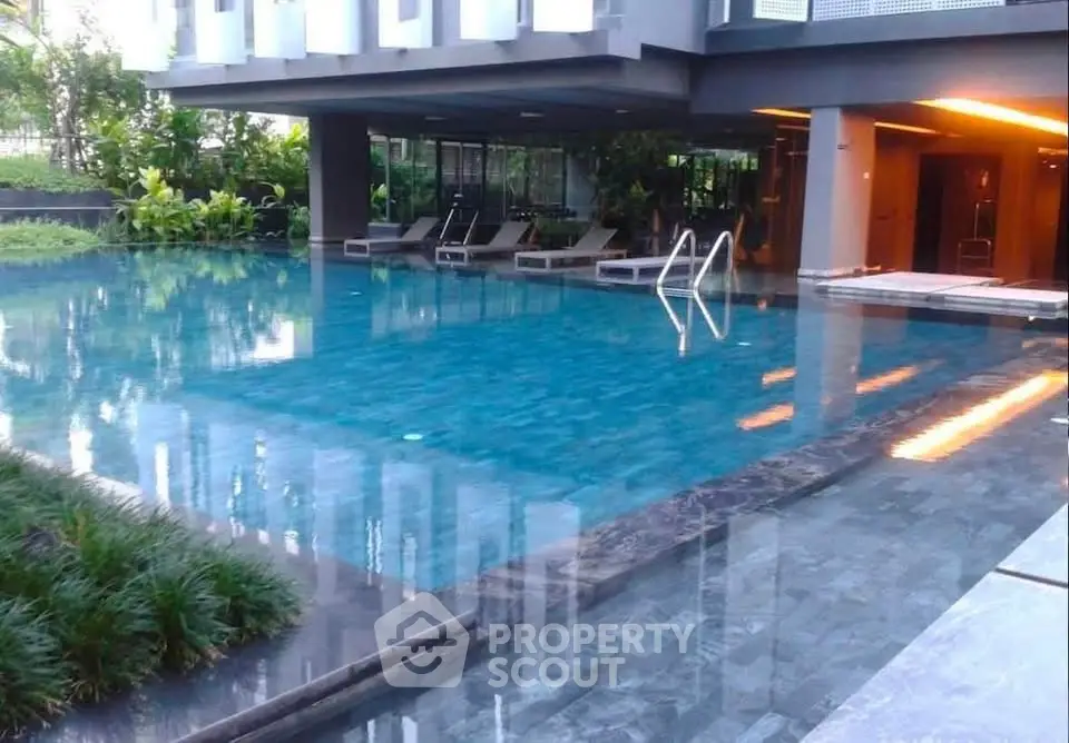 Luxurious modern apartment complex with serene swimming pool and lush greenery.