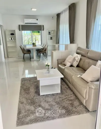 Modern living room with sleek leather sofa and elegant dining area, featuring large windows and stylish decor.