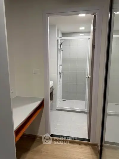 Modern bathroom with sleek shower and wooden flooring, perfect for contemporary living.