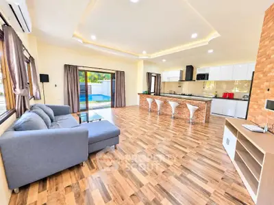 Spacious open-plan living room with modern kitchen and pool view, perfect for entertaining.
