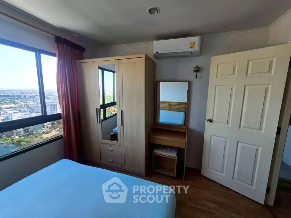 Cozy bedroom with city view, featuring a wardrobe, vanity, and air conditioning for comfortable living.