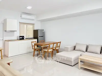Modern open-plan living room and kitchen with sleek furniture and appliances