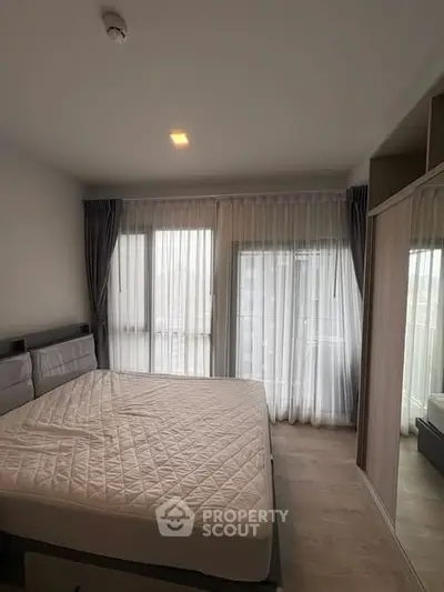 Spacious bedroom with large windows and modern decor in a stylish apartment.