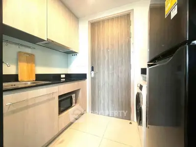 Modern kitchen with sleek appliances and wooden cabinetry in a compact layout.