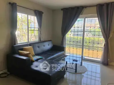 Modern living room with large windows and stylish black leather sofa