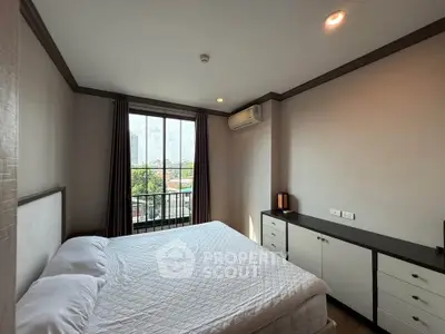 Cozy bedroom with large window and modern furnishings in a stylish apartment.