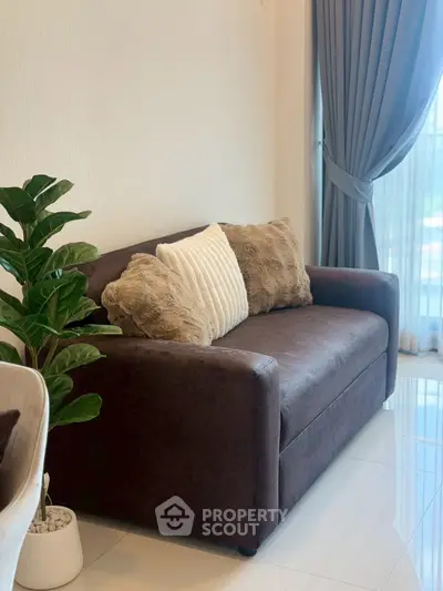 Cozy living room with plush brown sofa and elegant curtains, perfect for relaxation.