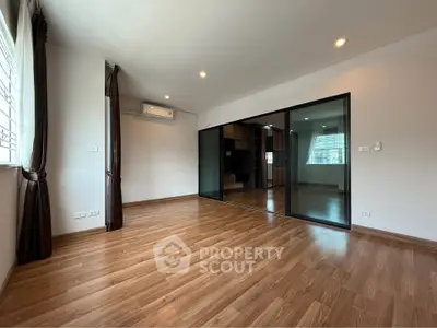 Spacious modern living room with wooden flooring and glass partition