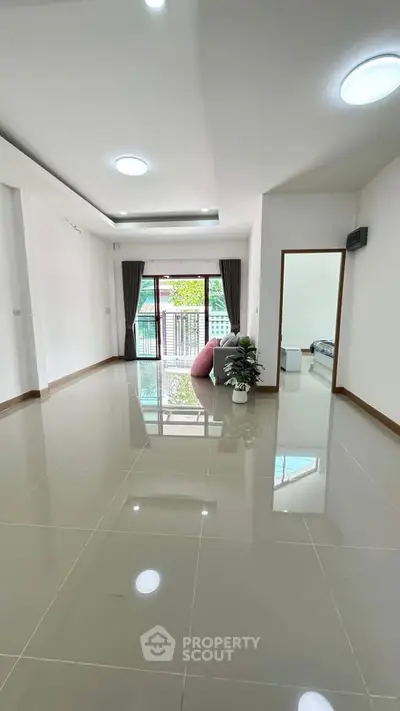 Spacious modern living room with glossy tiled floors and large window for natural light.