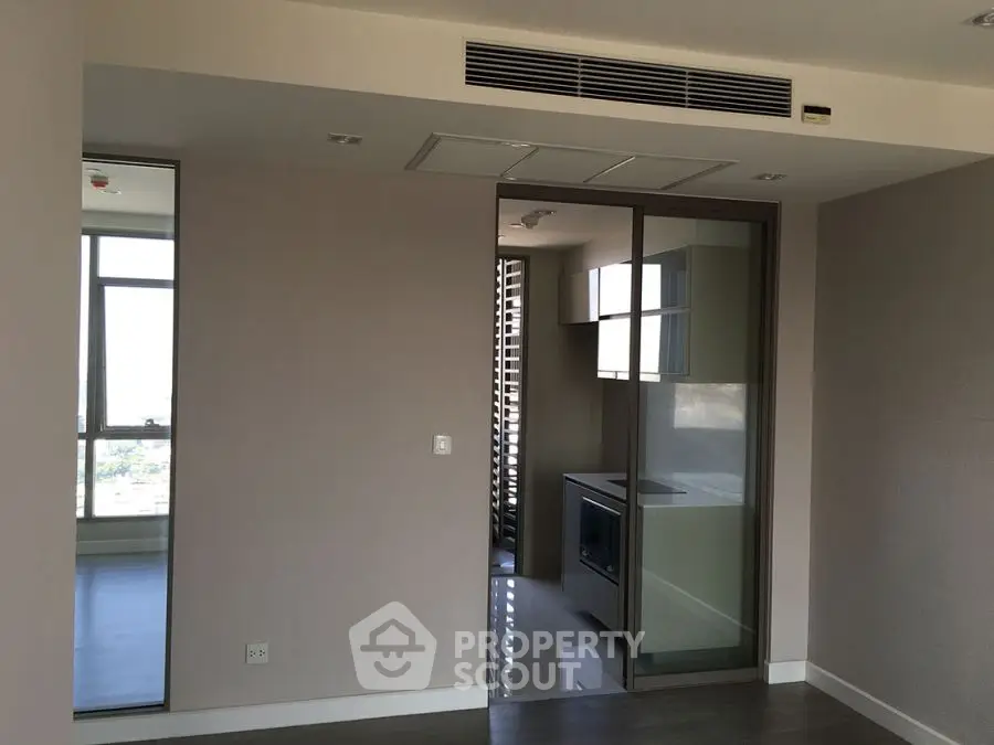 Modern apartment interior with sleek kitchen and large windows offering natural light.