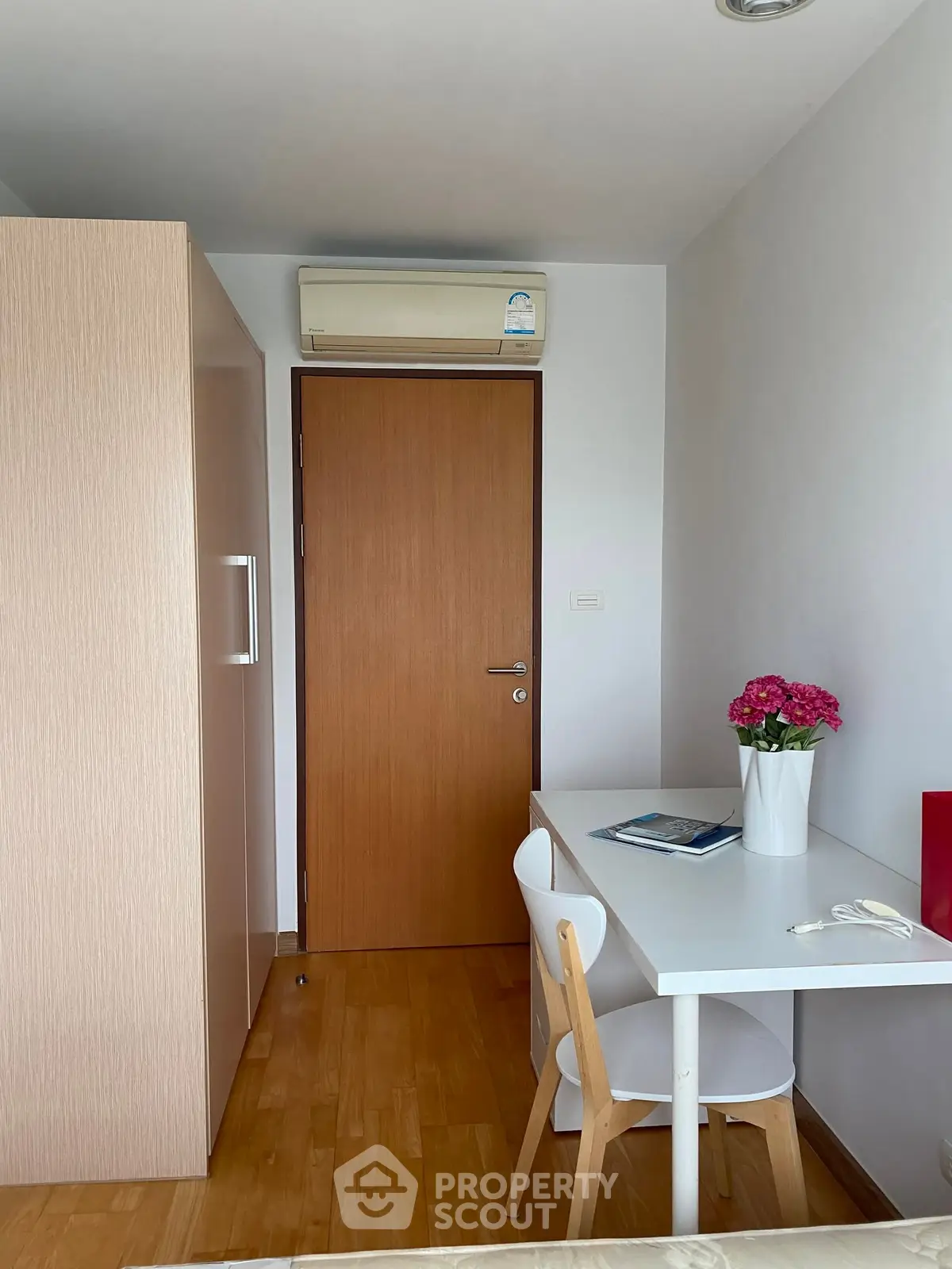 Cozy study nook with desk, chair, and vibrant flowers in modern apartment.