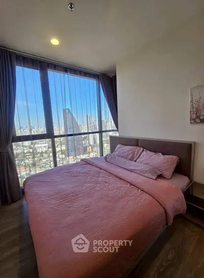 Modern bedroom with large windows offering stunning city view, featuring cozy pink bedding.