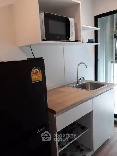 Modern compact kitchen with microwave and fridge in a stylish apartment