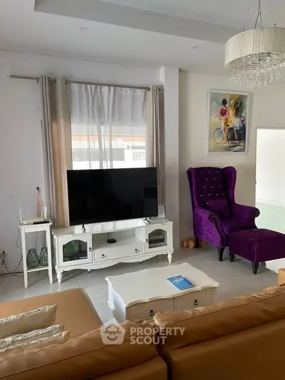 Elegant living room with modern decor, featuring a plush purple armchair and sleek TV setup.
