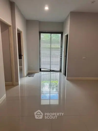 Spacious modern interior with glossy tiled floors and large window view.