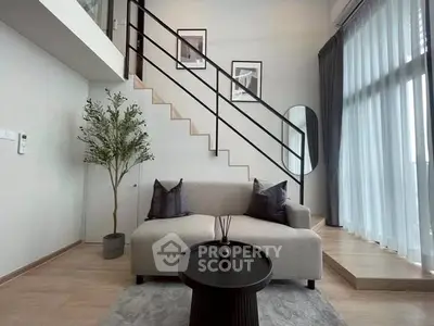 Modern living room with high ceiling and stylish staircase in a contemporary apartment.
