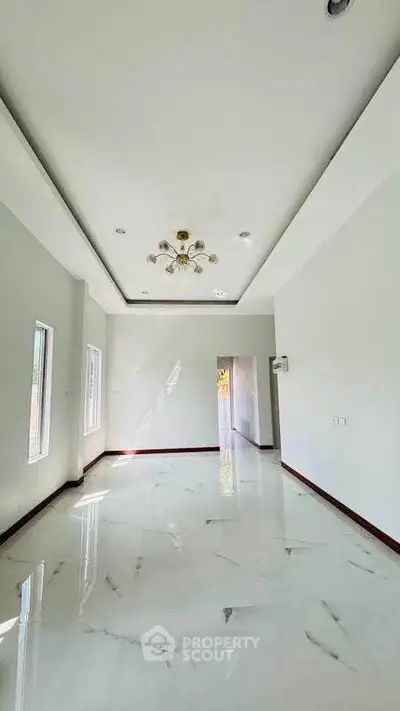 Spacious and bright living room with elegant chandelier and glossy marble flooring.