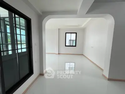 Spacious modern living room with large windows and sleek white flooring.