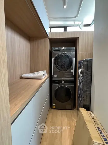 Modern laundry area with stacked washer and dryer in sleek wooden cabinetry.