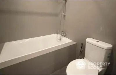 Sleek modern bathroom with a pristine white bathtub and matching toilet, featuring minimalist fixtures and neutral tones for a serene ambiance.