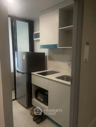 Compact modern kitchen with sleek appliances and minimalist design in a cozy apartment.