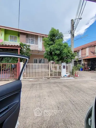 Charming townhouse with gated entrance and lush greenery in a serene neighborhood.