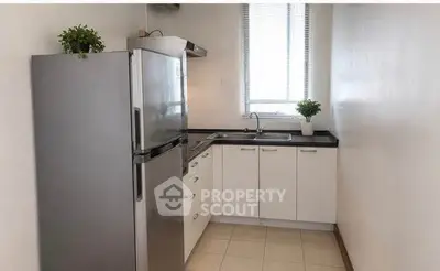 Modern kitchen with sleek cabinets and stainless steel fridge in a bright apartment.