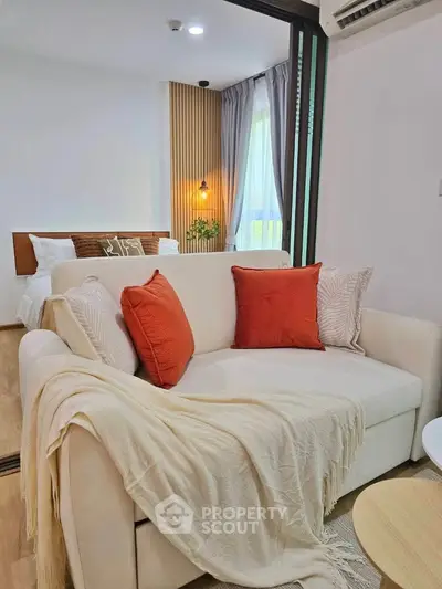 Modern living room with cozy sofa and stylish decor leading to a bright bedroom.