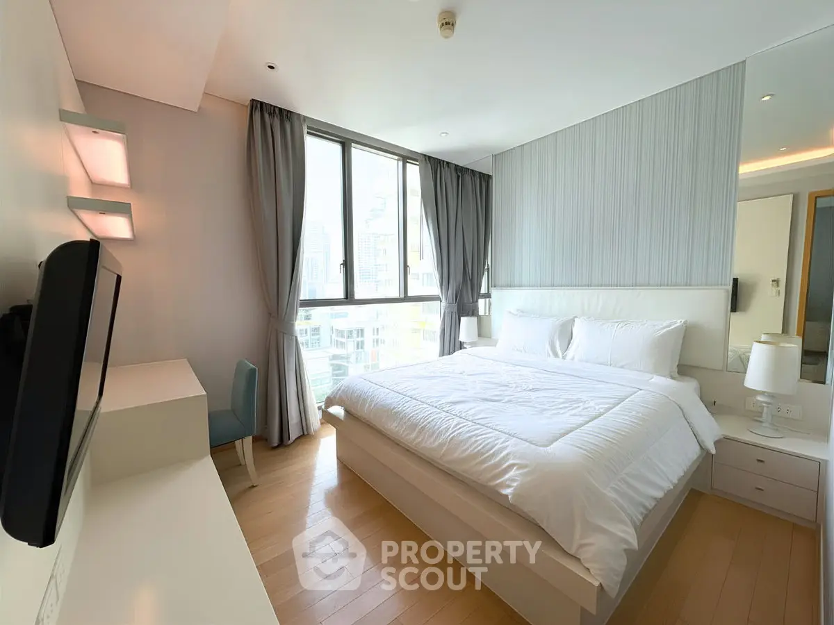 Spacious modern bedroom with large window and stylish decor in urban apartment.