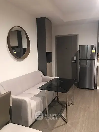 Modern living room with sleek furniture and stainless steel fridge in a stylish apartment.