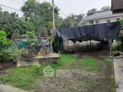 Spacious backyard with greenery and covered area, ideal for outdoor activities and gardening.