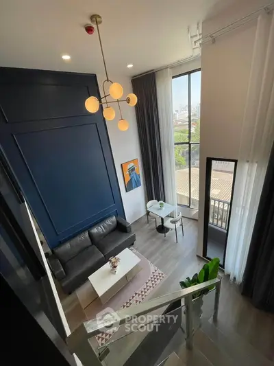 Modern loft-style living room with high ceilings and large windows offering city views.