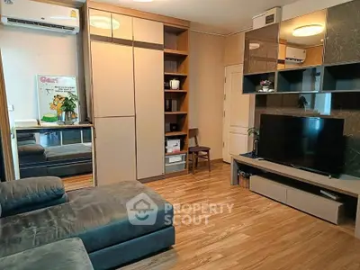 Modern living room with sleek furniture and built-in storage, featuring a large TV and stylish decor.