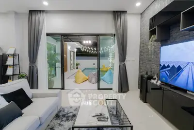 Luxurious living room with pool view, modern decor, and cozy seating area.