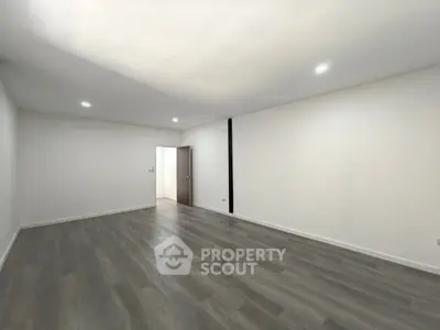 Spacious empty room with modern flooring and recessed lighting, perfect for customization.