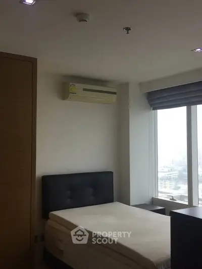 Cozy bedroom with large window and city view, featuring modern air conditioning and minimalist design.