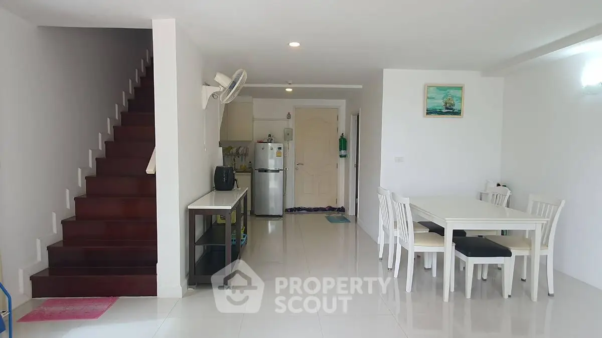 Spacious open-plan living area with modern dining set and sleek kitchen in a bright home.