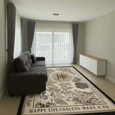 Spacious living room with elegant carpet and modern sofa, featuring large windows with curtains.