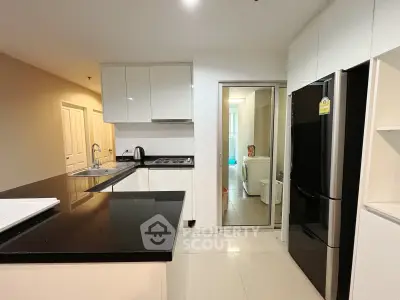 Modern kitchen with sleek black countertops and stainless steel appliances in a contemporary apartment.