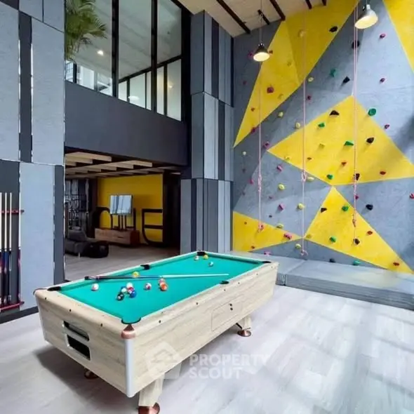 Modern recreational room with pool table and climbing wall in luxury building.